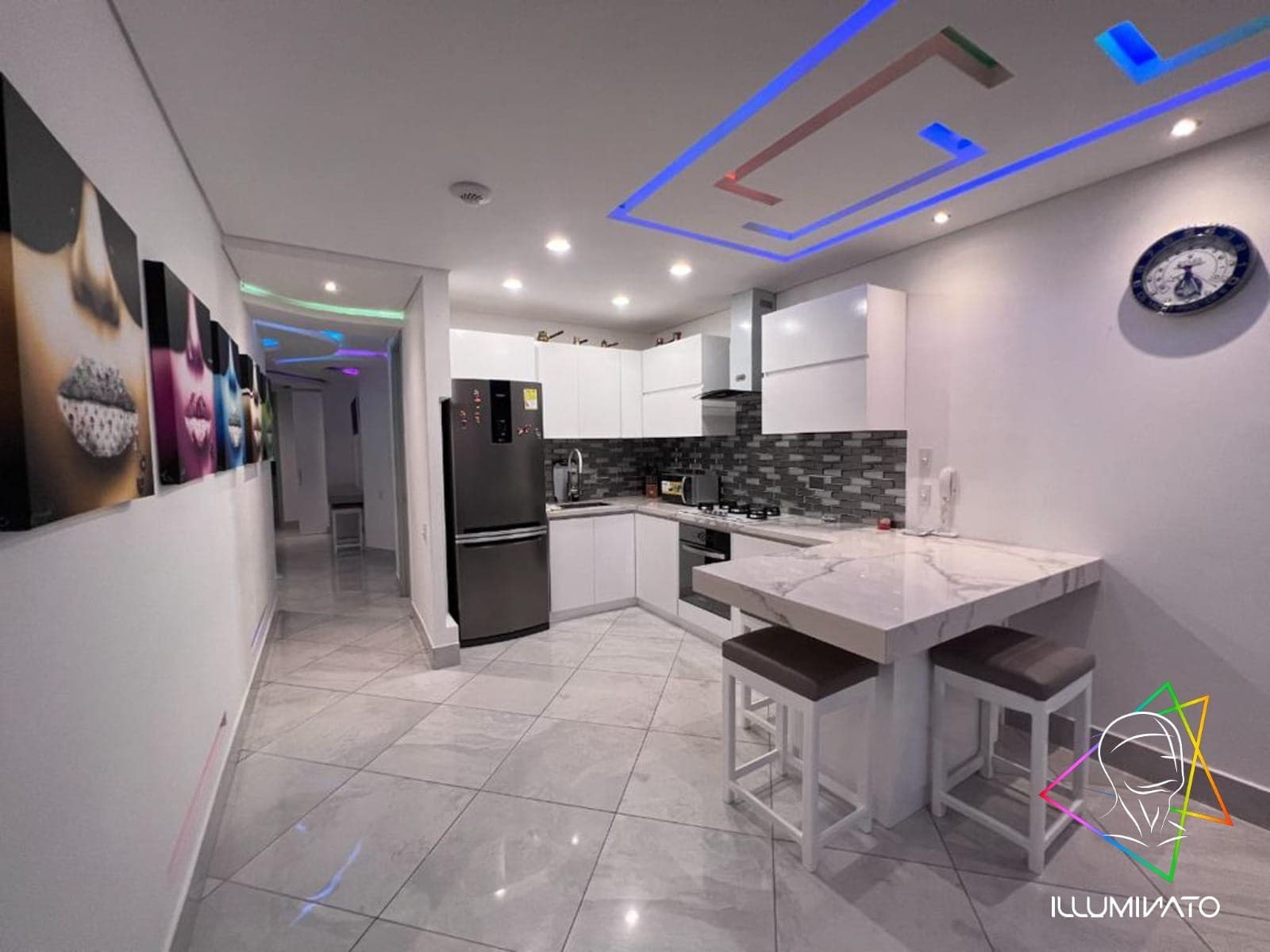 Cocina integral blanca abierta al comedor, con iluminación LED en el cielorraso.