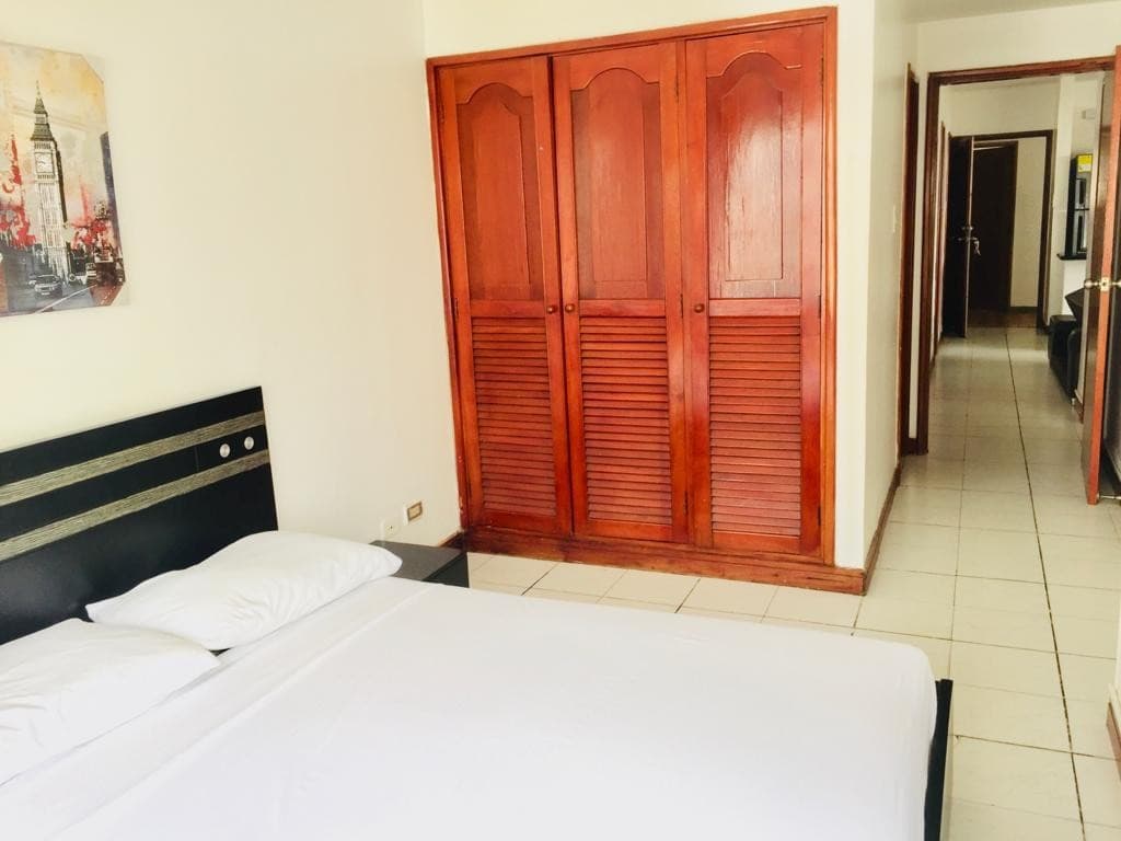 Alcoba con cama doble y clóset de madera, con el pasillo al fondo.