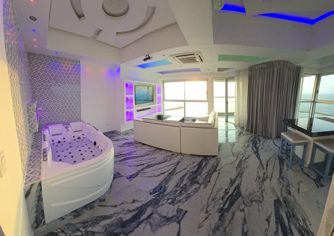 Sala con jacuzzi, piso en mármol e iluminación LED, con el ventanal al mar.