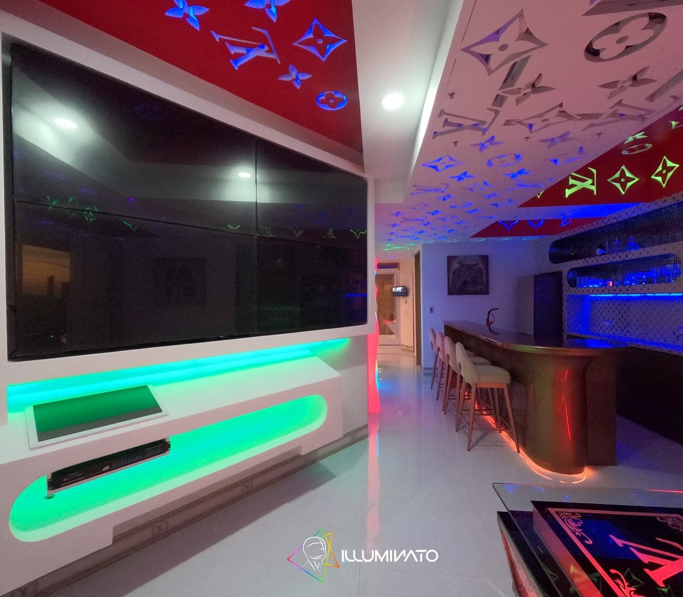 Televisor de pantalla grande sobre mueble con luz LED, junto a la barra.