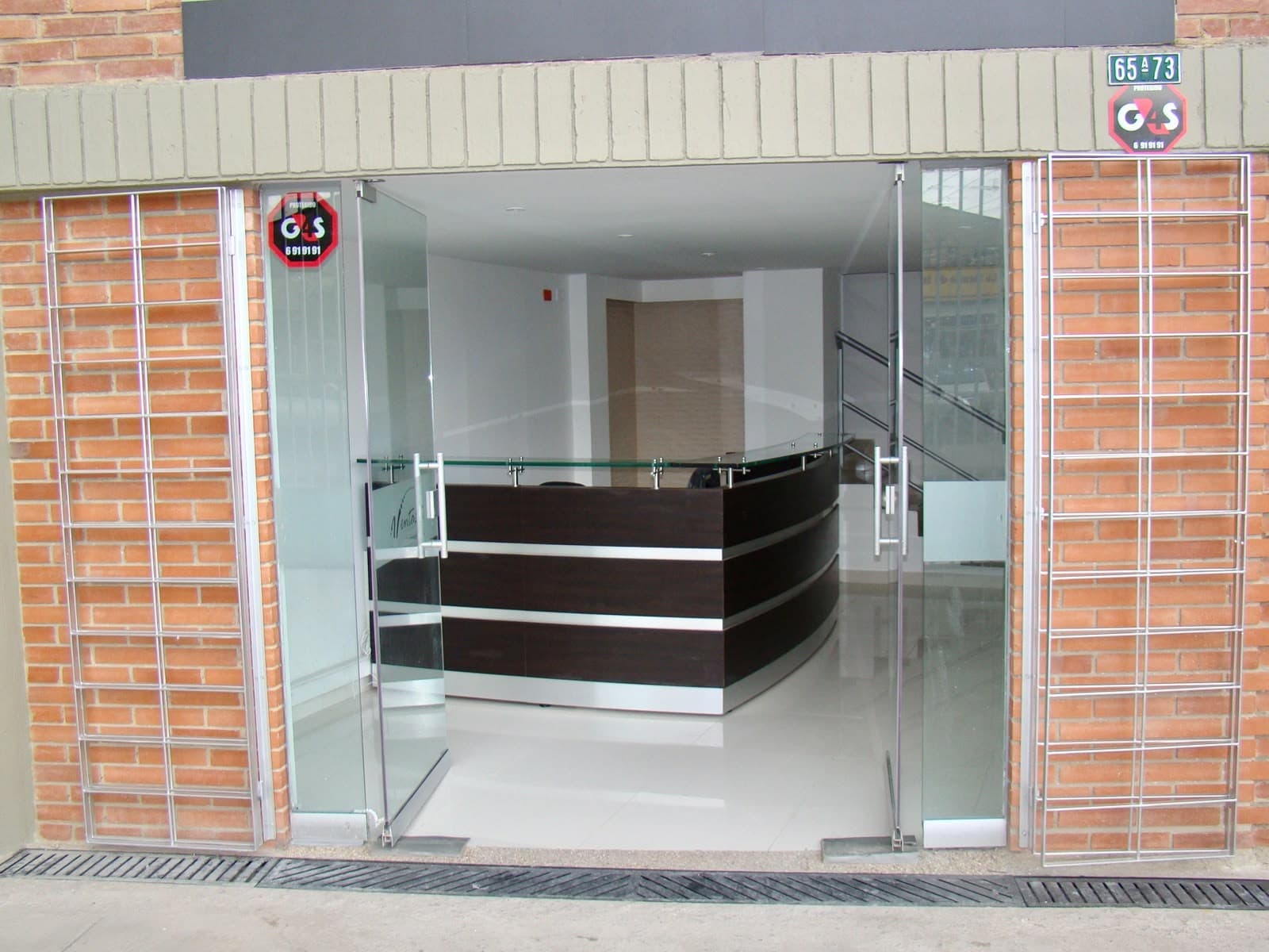 Entrada principal en vidrio, con la recepción al fondo.