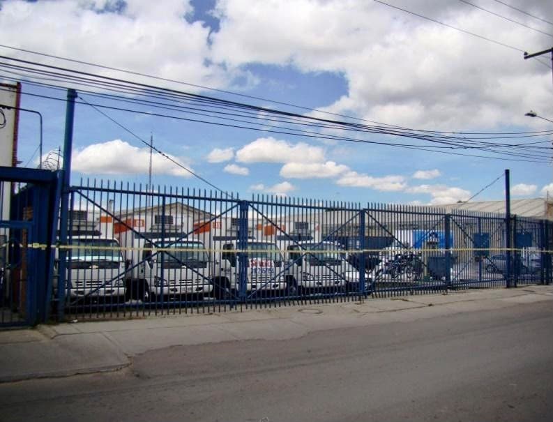 Cierre perimetral en reja sobre la calle, con el patio al fondo.