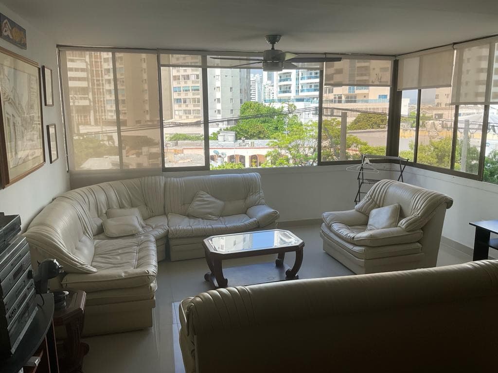Sala con juego de muebles en cuero claro junto a los ventanales esquineros.