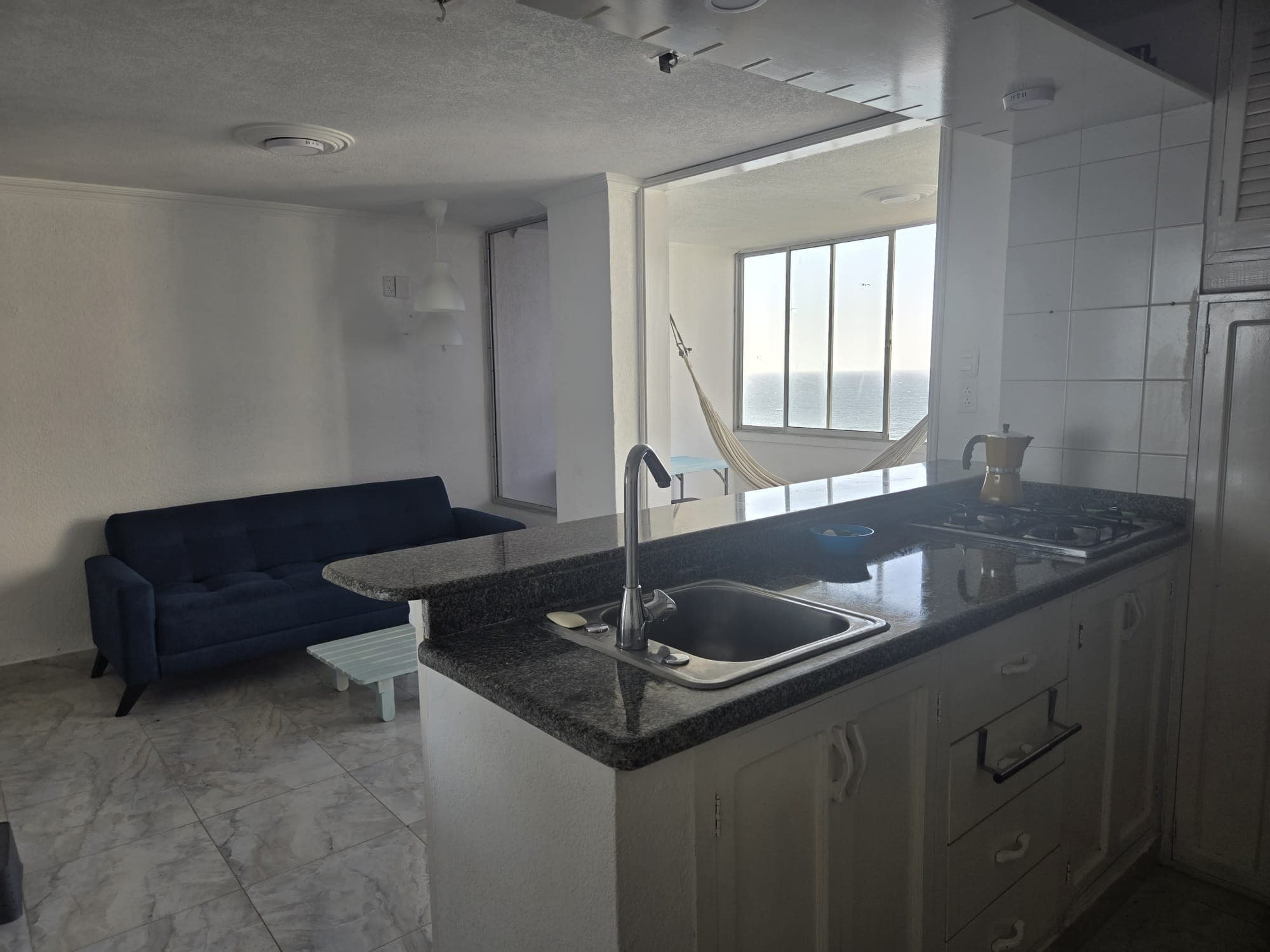 Cocina con mesón en granito y poceta, abierta a la sala.
