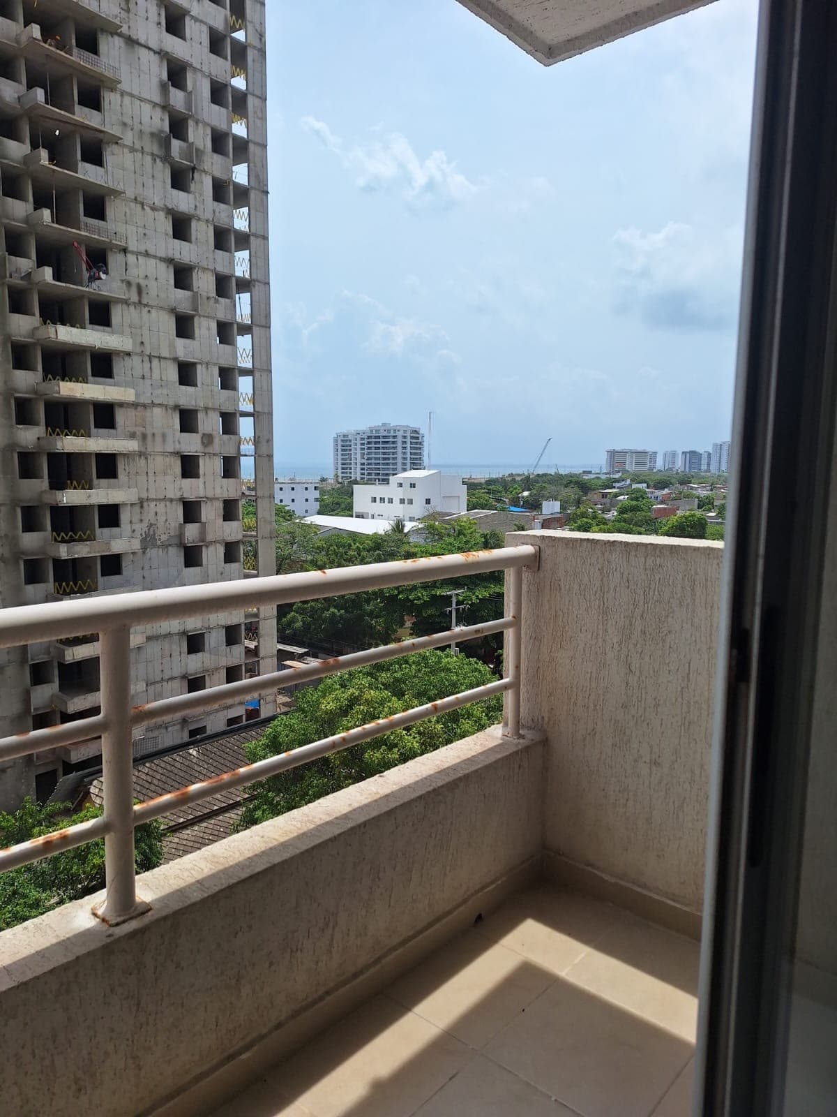Balcón del apartamento con vista a las torres vecinas y al mar.