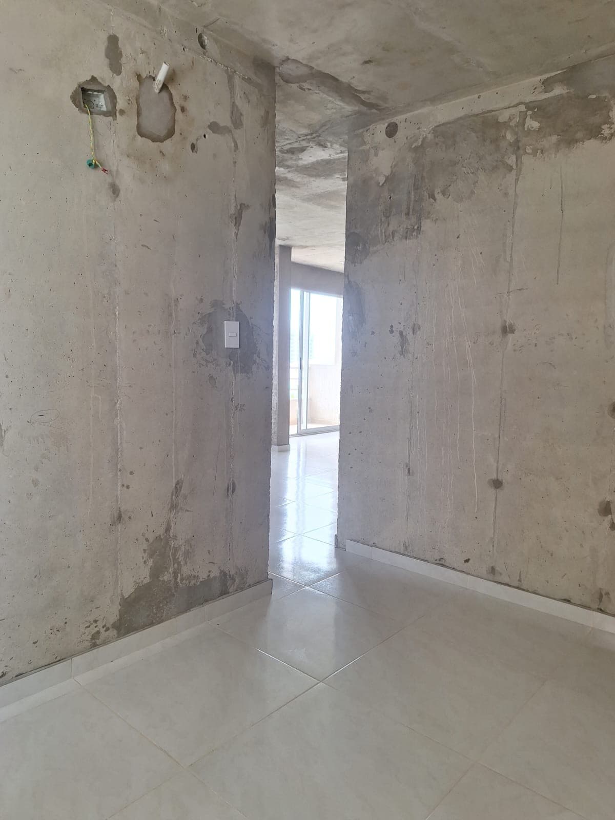 Alcoba en obra gris con muros sin acabado y piso en baldosa.