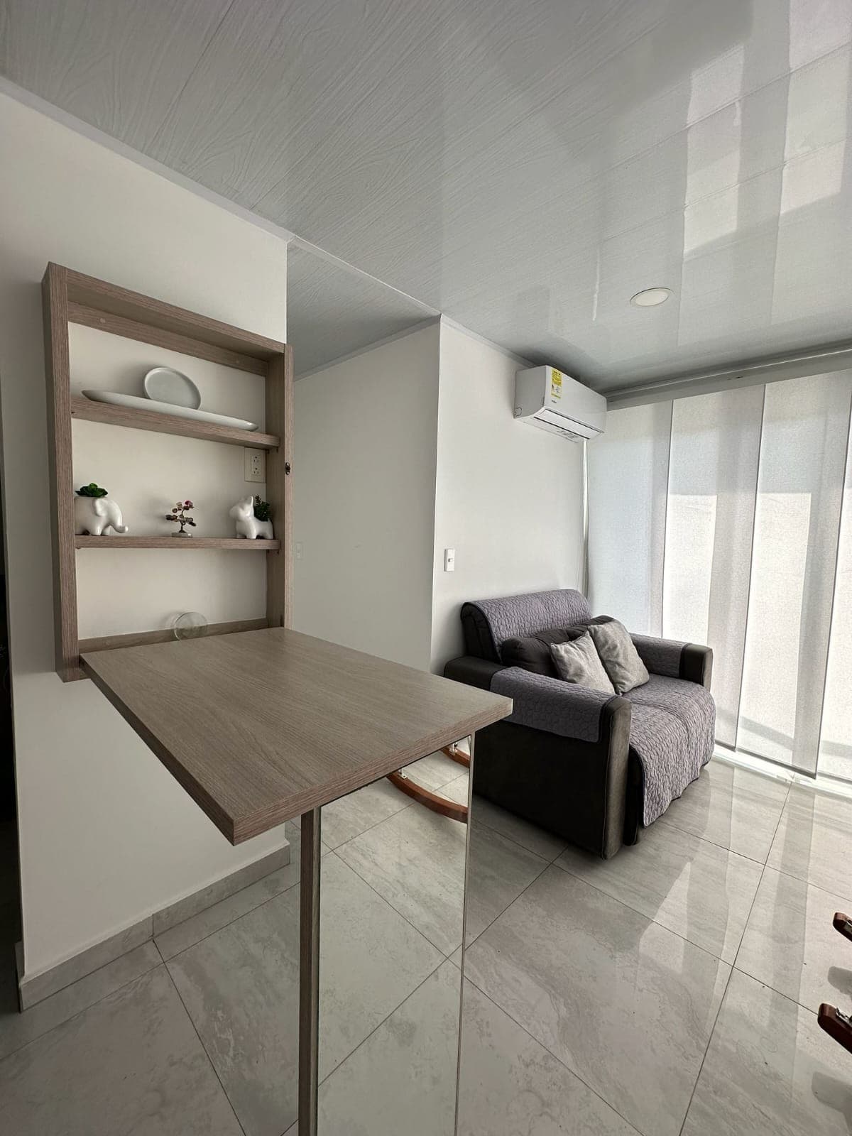 Sala con sofá, mesa auxiliar abatible y repisa de madera.