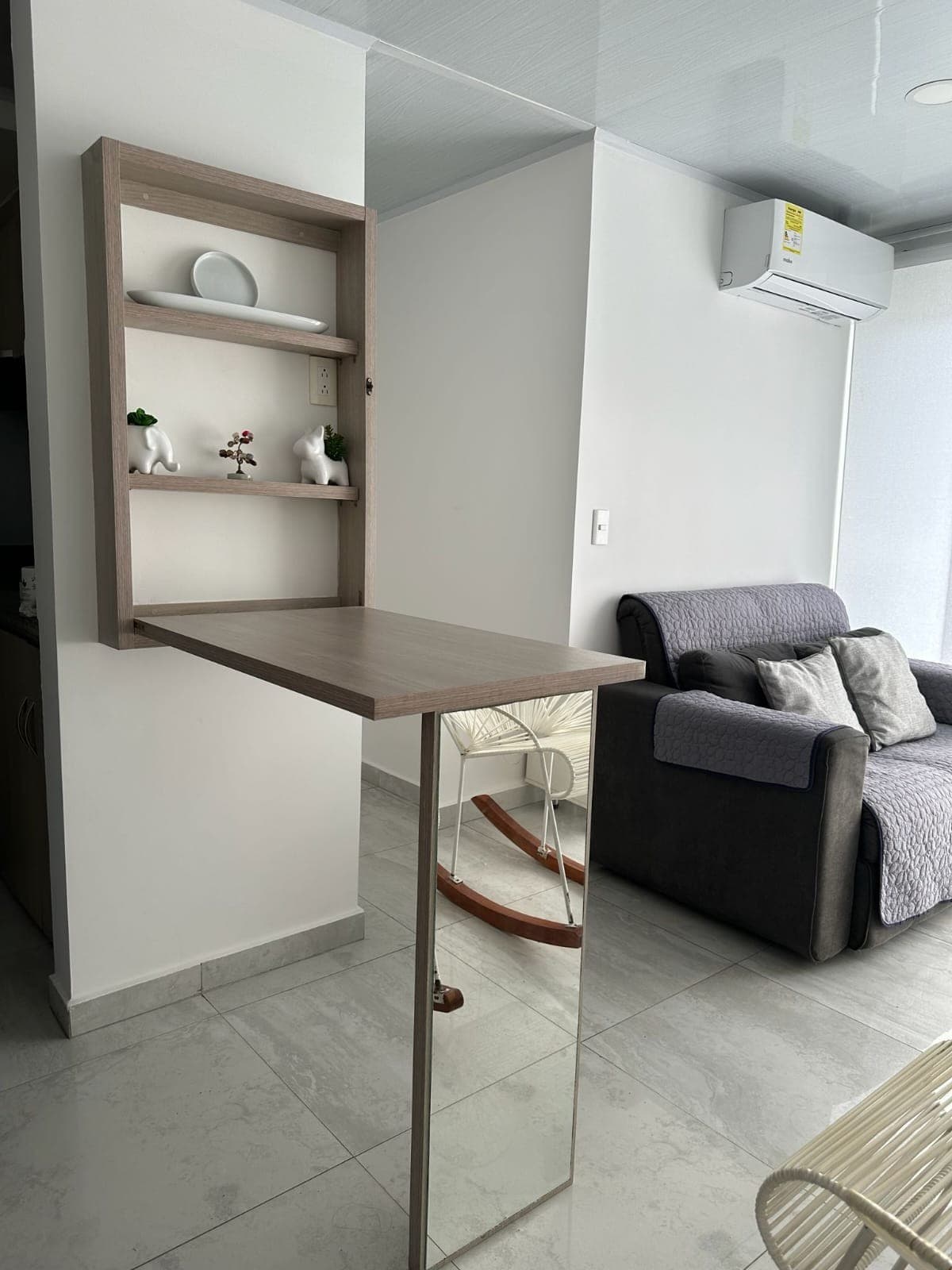 Sala vista desde el comedor, con la mesa abatible y el espejo de pared.
